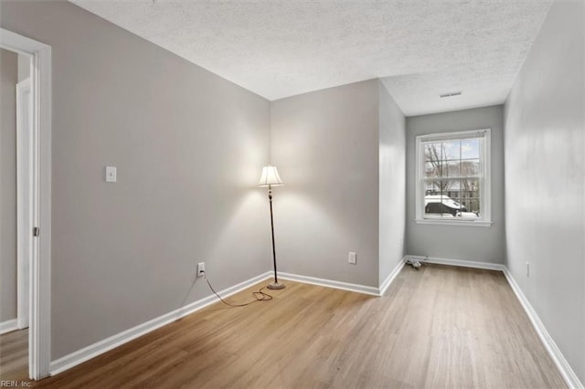 unfurnished room featuring wood-type flooring and a textured ceiling