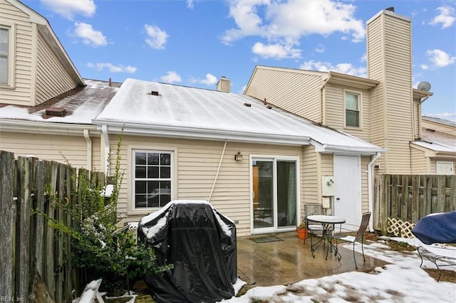 snow covered rear of property with a patio