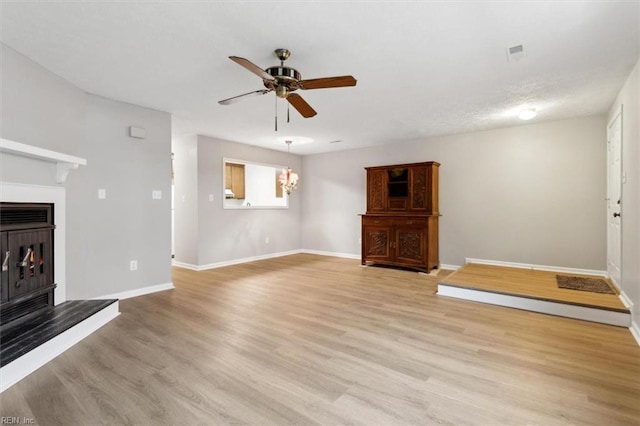 unfurnished living room featuring ceiling fan with notable chandelier and light hardwood / wood-style floors