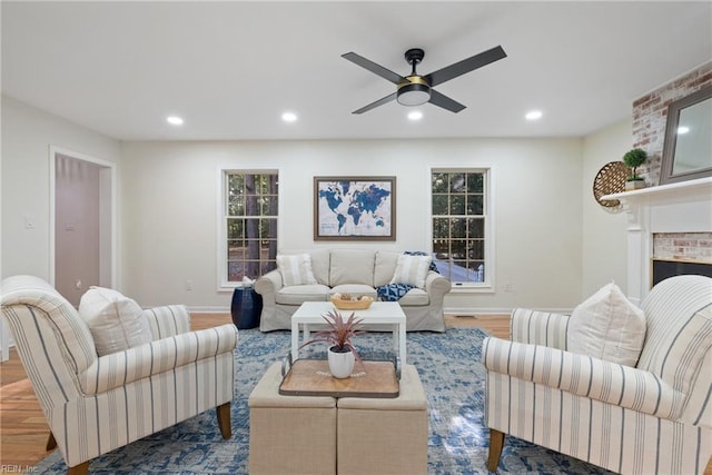 living room featuring hardwood / wood-style floors, ceiling fan, and a brick fireplace