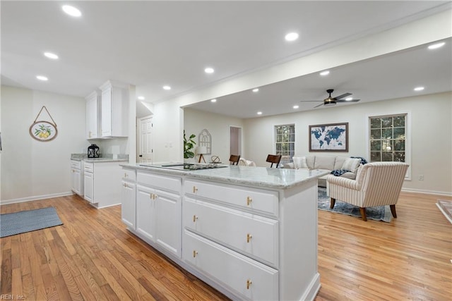 kitchen with white cabinets, black electric stovetop, a center island, and light hardwood / wood-style flooring