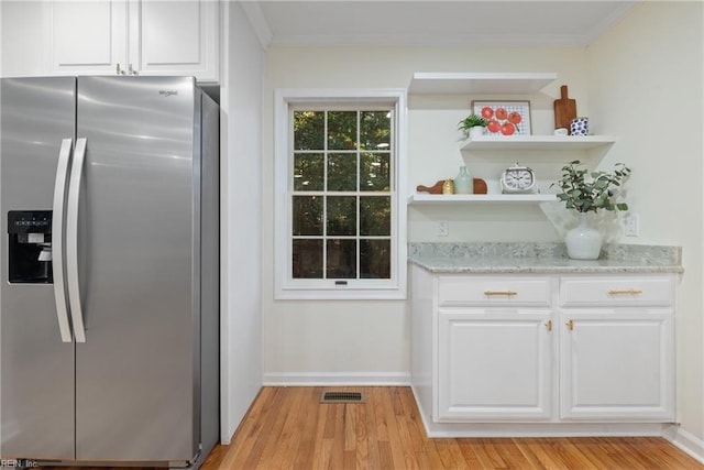 kitchen with light stone countertops, white cabinets, stainless steel refrigerator with ice dispenser, and light wood-type flooring