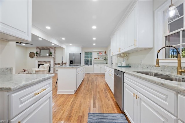 kitchen with sink, a fireplace, decorative light fixtures, a kitchen island, and stainless steel appliances