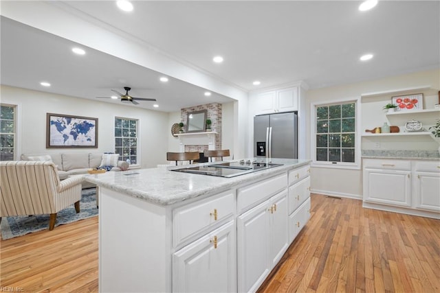 kitchen featuring a center island, white cabinets, black electric stovetop, stainless steel refrigerator with ice dispenser, and light hardwood / wood-style floors