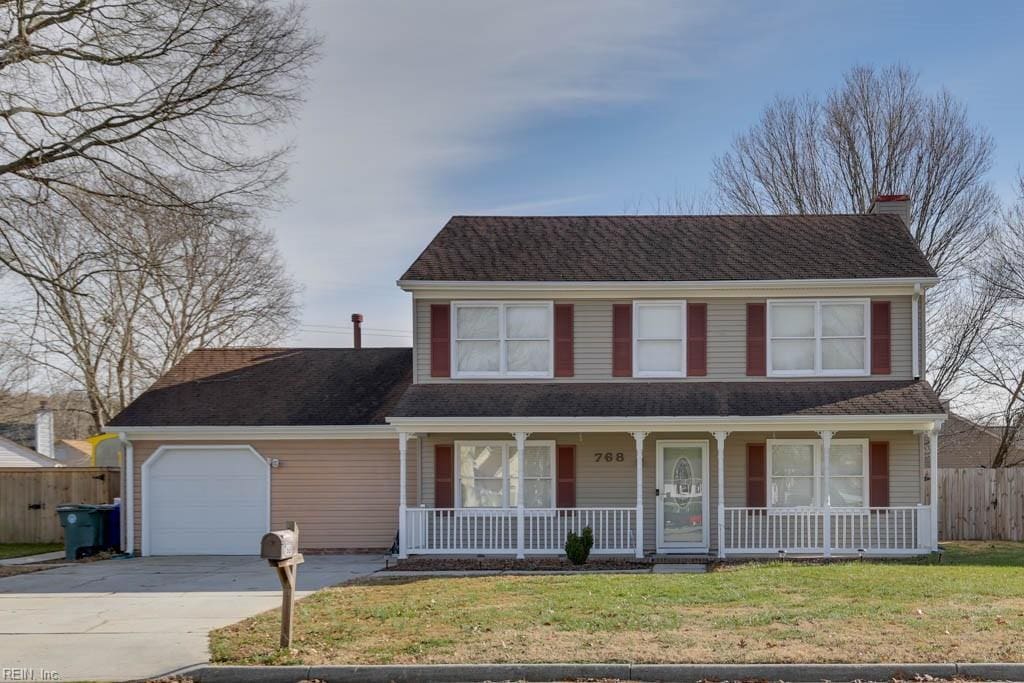 view of front of home with covered porch, a garage, and a front lawn