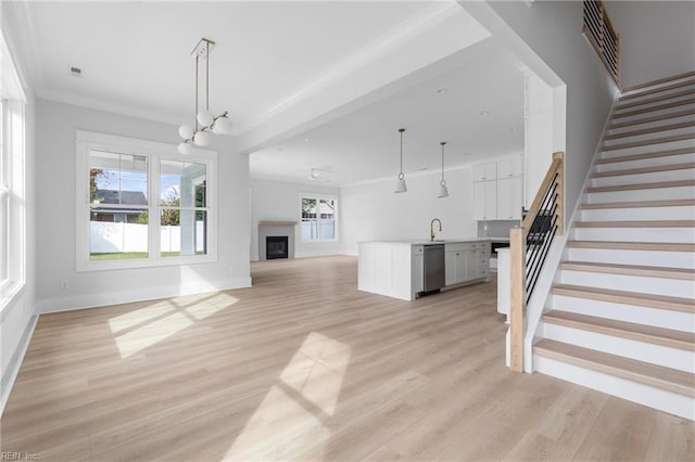 unfurnished living room with light hardwood / wood-style floors, sink, a wealth of natural light, and a chandelier