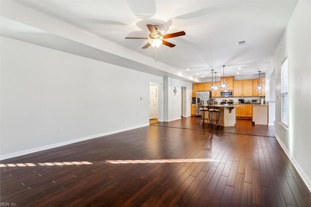 unfurnished living room with ceiling fan and dark wood-type flooring