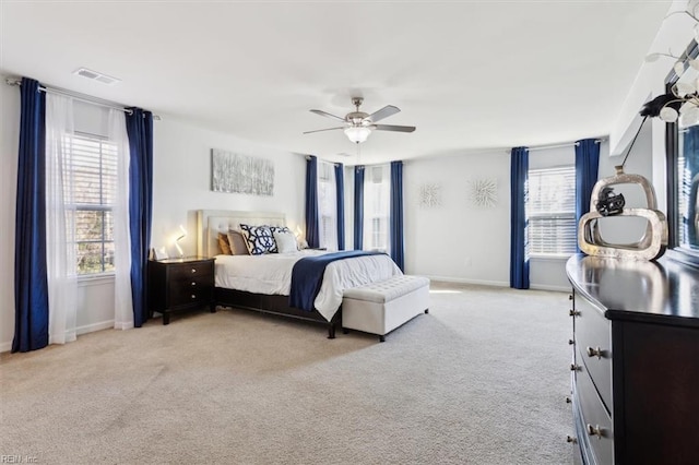 bedroom featuring ceiling fan, light carpet, and multiple windows