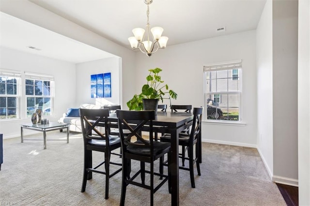 dining space with carpet flooring and a notable chandelier