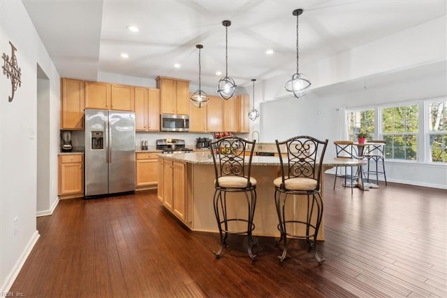 kitchen featuring light stone countertops, dark wood-type flooring, stainless steel appliances, decorative light fixtures, and light brown cabinetry