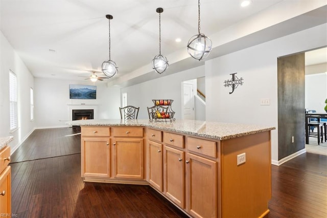 kitchen with dark hardwood / wood-style flooring, decorative light fixtures, a kitchen island, and ceiling fan