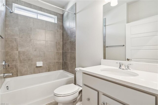 full bathroom with tiled shower / bath combo, toilet, and vanity