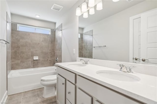 full bathroom with tile patterned flooring, vanity, tiled shower / bath combo, and toilet