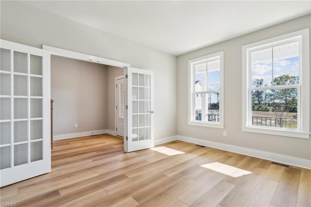 spare room featuring french doors and light hardwood / wood-style floors