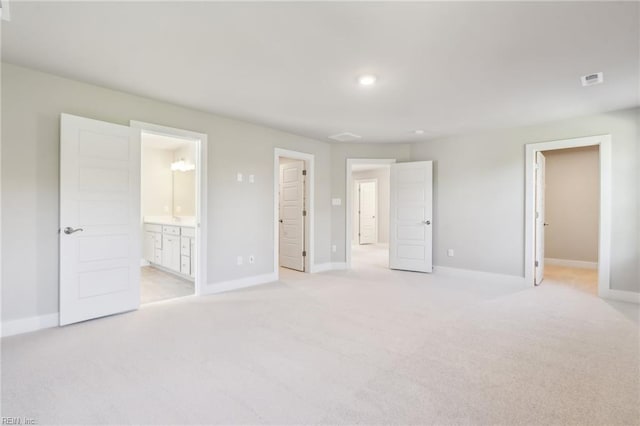 unfurnished bedroom featuring connected bathroom and light carpet