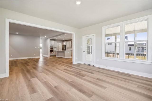 unfurnished living room featuring light wood-type flooring and a wealth of natural light