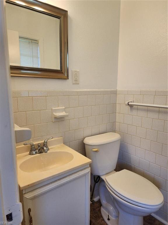 bathroom with vanity, toilet, and tile walls