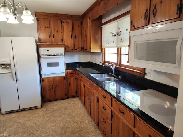 kitchen with sink, hanging light fixtures, white appliances, and a notable chandelier