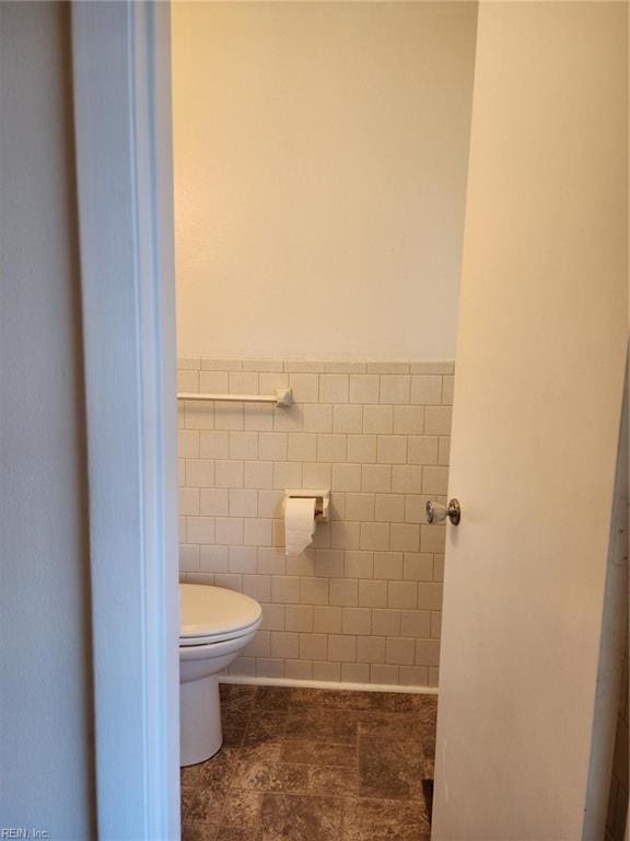 bathroom with tile walls and toilet