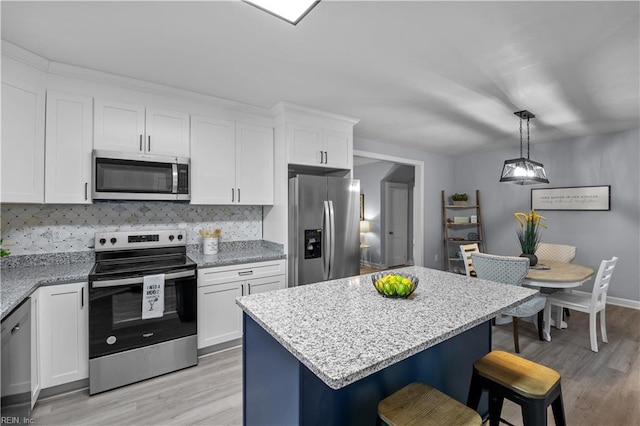 kitchen featuring a center island, stainless steel appliances, tasteful backsplash, decorative light fixtures, and white cabinets