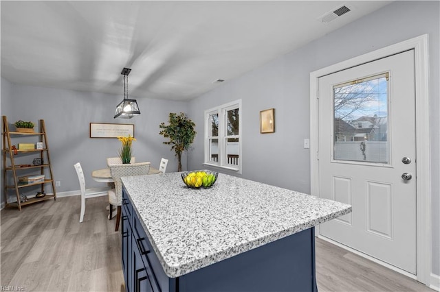 kitchen with blue cabinetry, a center island, decorative light fixtures, and light hardwood / wood-style floors