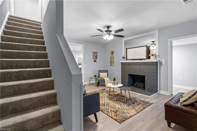 living room with ceiling fan, a fireplace, and light hardwood / wood-style flooring