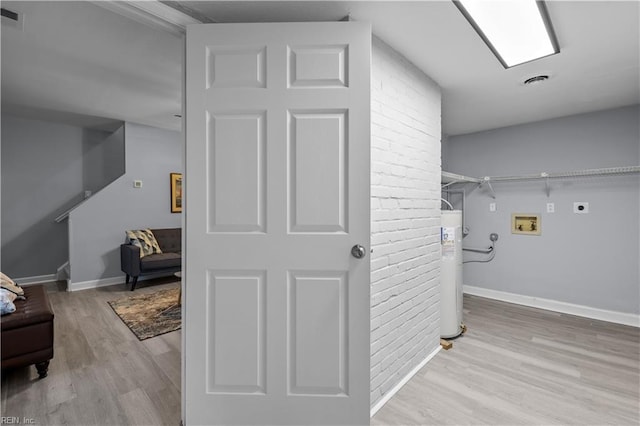 interior space with hookup for an electric dryer, electric water heater, hookup for a washing machine, and light hardwood / wood-style flooring