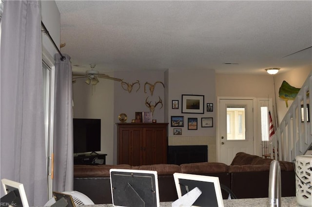 living room with ceiling fan and a textured ceiling