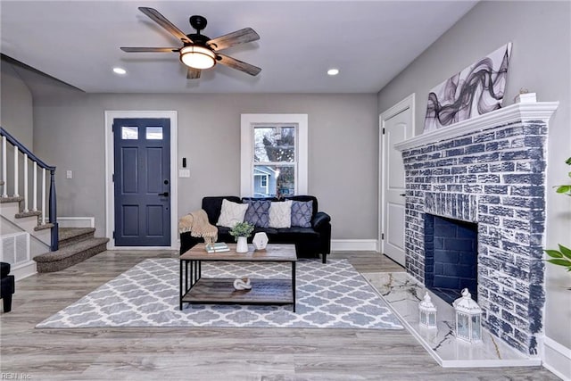 living room featuring hardwood / wood-style flooring, ceiling fan, and a fireplace