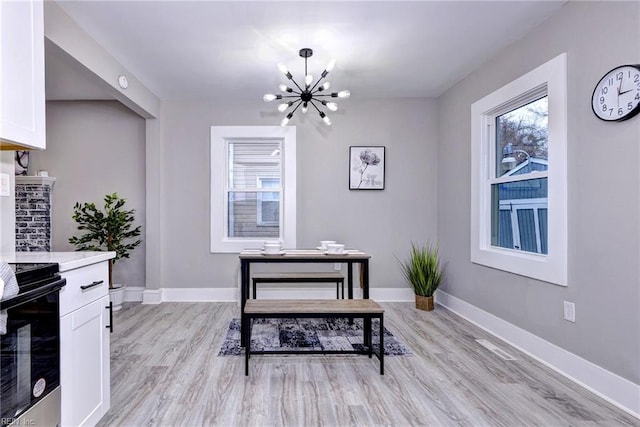 dining room with light hardwood / wood-style flooring and an inviting chandelier