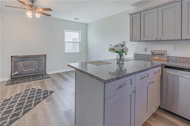 kitchen featuring dishwasher, kitchen peninsula, dark stone counters, gray cabinets, and light wood-type flooring