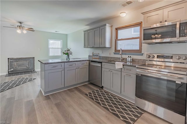 kitchen featuring sink, ceiling fan, gray cabinets, kitchen peninsula, and stainless steel appliances