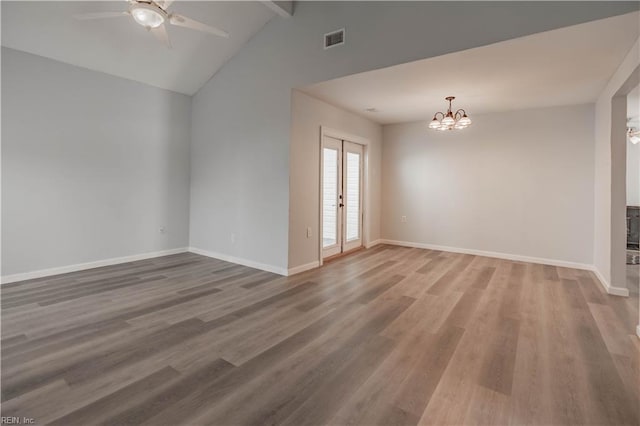 spare room featuring hardwood / wood-style floors, ceiling fan with notable chandelier, lofted ceiling with beams, and french doors