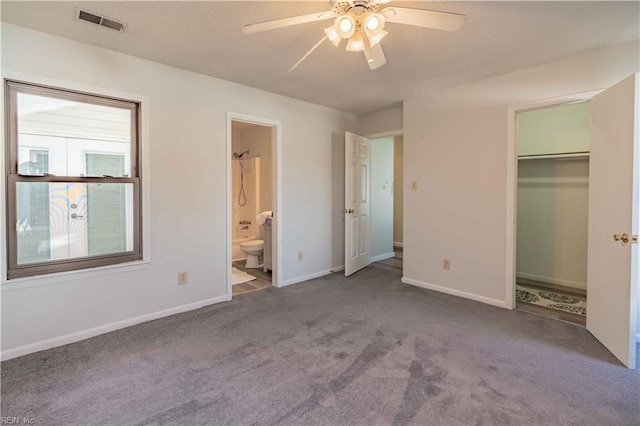 unfurnished bedroom with a closet, light colored carpet, ensuite bath, and ceiling fan