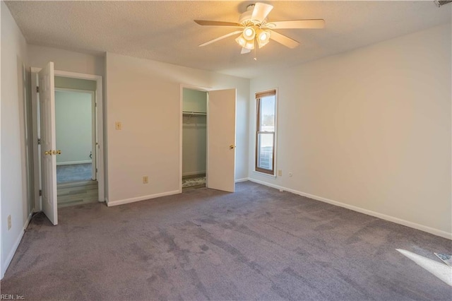 unfurnished bedroom featuring a textured ceiling, a closet, dark carpet, and ceiling fan