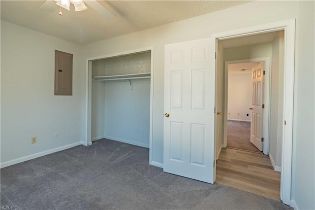 unfurnished bedroom featuring a closet, electric panel, dark carpet, and ceiling fan