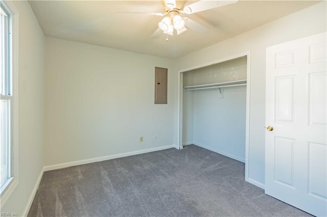 unfurnished bedroom with ceiling fan, dark carpet, electric panel, and a closet