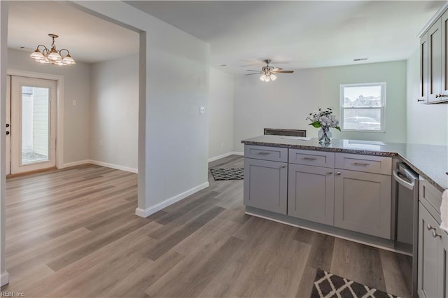 kitchen featuring ceiling fan with notable chandelier, dishwasher, hardwood / wood-style floors, gray cabinets, and hanging light fixtures