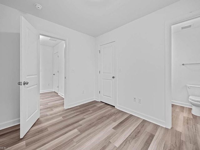 unfurnished bedroom featuring ensuite bath and light wood-type flooring