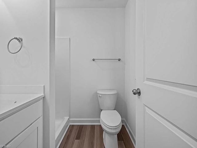 bathroom with a shower, hardwood / wood-style floors, vanity, and toilet