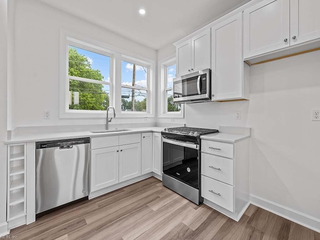 kitchen with plenty of natural light, white cabinetry, sink, and appliances with stainless steel finishes