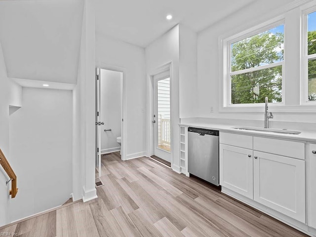 kitchen featuring white cabinets, stainless steel dishwasher, a wealth of natural light, and sink