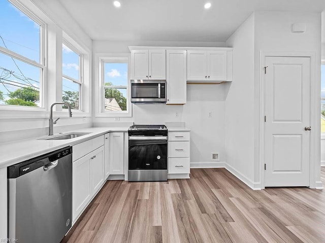 kitchen with white cabinets, light wood-type flooring, sink, and appliances with stainless steel finishes