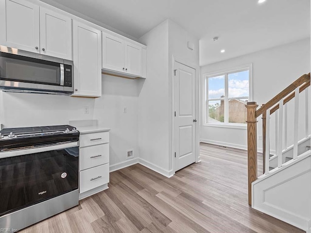 kitchen with white cabinets, light wood-type flooring, and stainless steel appliances