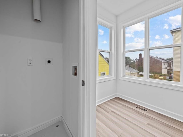 clothes washing area featuring hookup for a washing machine, light hardwood / wood-style floors, plenty of natural light, and electric dryer hookup