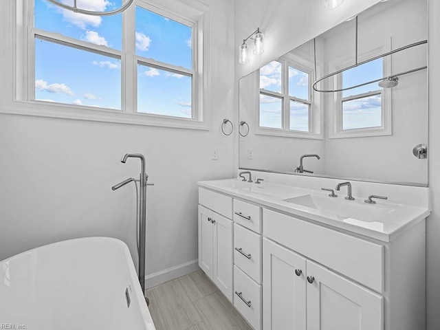 bathroom featuring plenty of natural light, a tub to relax in, and vanity