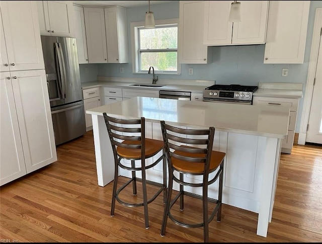 kitchen with appliances with stainless steel finishes, sink, decorative light fixtures, white cabinets, and a kitchen island