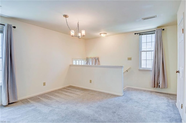 unfurnished room with light carpet and a chandelier