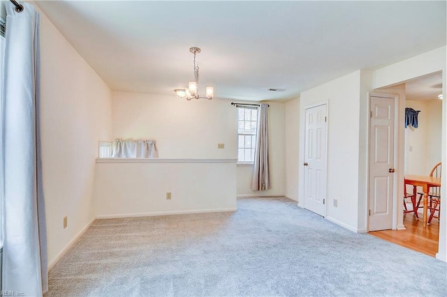 carpeted spare room featuring a chandelier