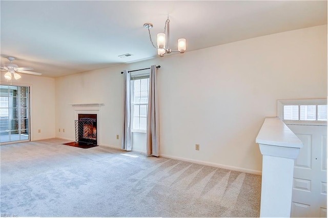 unfurnished living room with ceiling fan with notable chandelier and light colored carpet